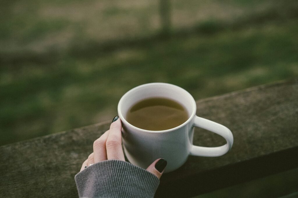 a woman's hand holding a cup of coffee, Moronel Tea Benefits
